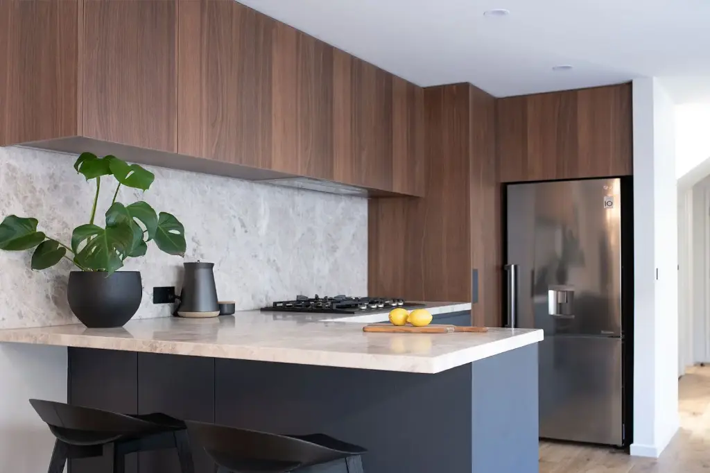 Cuisine en U – En Noyer de Bourgogne, avec un plan de travail en quartz.