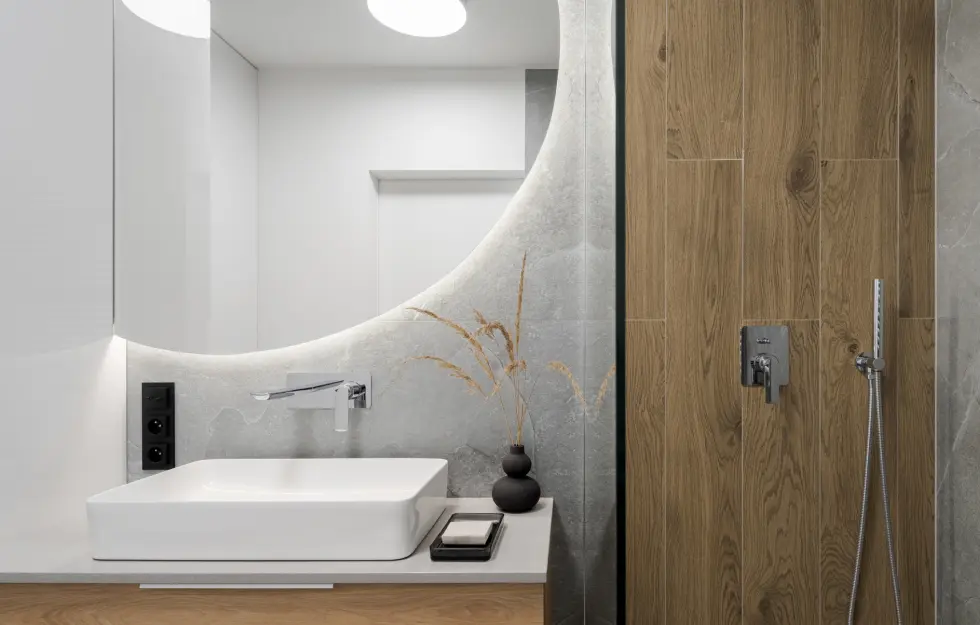 Salle de bain moderne avec miroir organique et finitions en bois et pierre