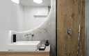 Salle de bain moderne avec miroir organique et finitions en bois et pierre